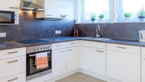 A modern kitchen with white cabinets, a built-in oven, a microwave, and a stainless steel range hood. - Appartement in Unterburg Am Klopeiner See by Interhome (Klopeiner See)