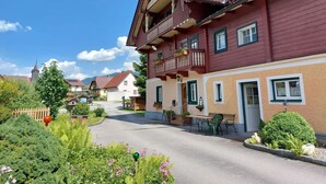 Ein traditionelles europäisches Gebäude mit Balkon, einer Straße davor und einer Kirche im Hintergrund.