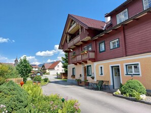 Ein traditionelles europäisches Gebäude mit Balkon, einer Straße davor und einer Kirche im Hintergrund.