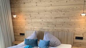 Une chambre à coucher moderne avec une tête de lit en bois, un lit agrémenté de plusieurs oreillers et une couverture bleue.