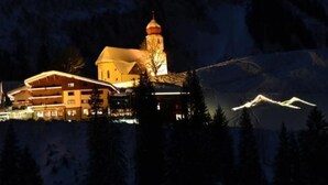 Un hôtel doté d’une tour imposante et de plusieurs bâtiments, entouré de montagnes enneigées.
