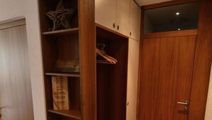 Un dressing accessible sans porte, doté d’étagères et de placards en bois, d’une porte en verre et d’un tapis à motifs sur le sol.