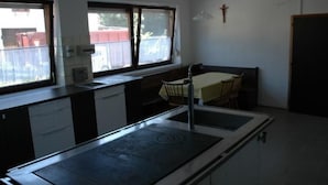 Cocina con estufa, lavamanos y ventana que da a una zona vallada.
