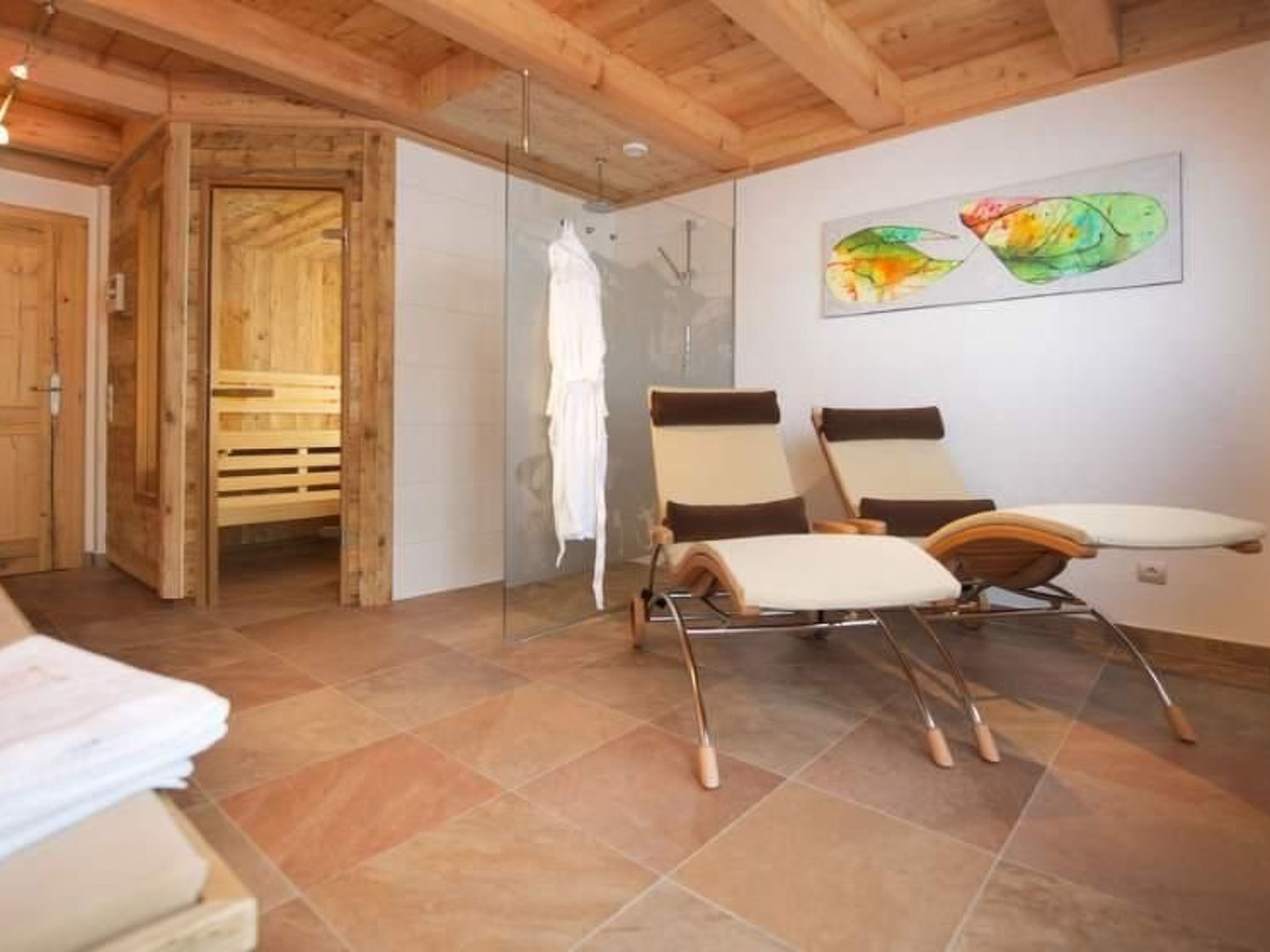 A spa room with wooden beams, a glass shower, and two reclining chairs.