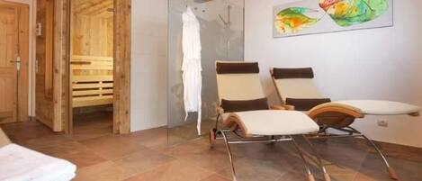 A spa room with wooden beams, a glass shower, and two reclining chairs.