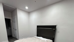 Een slaapkamer met een bed, een plafondventilator en een deur naar een andere kamer.
