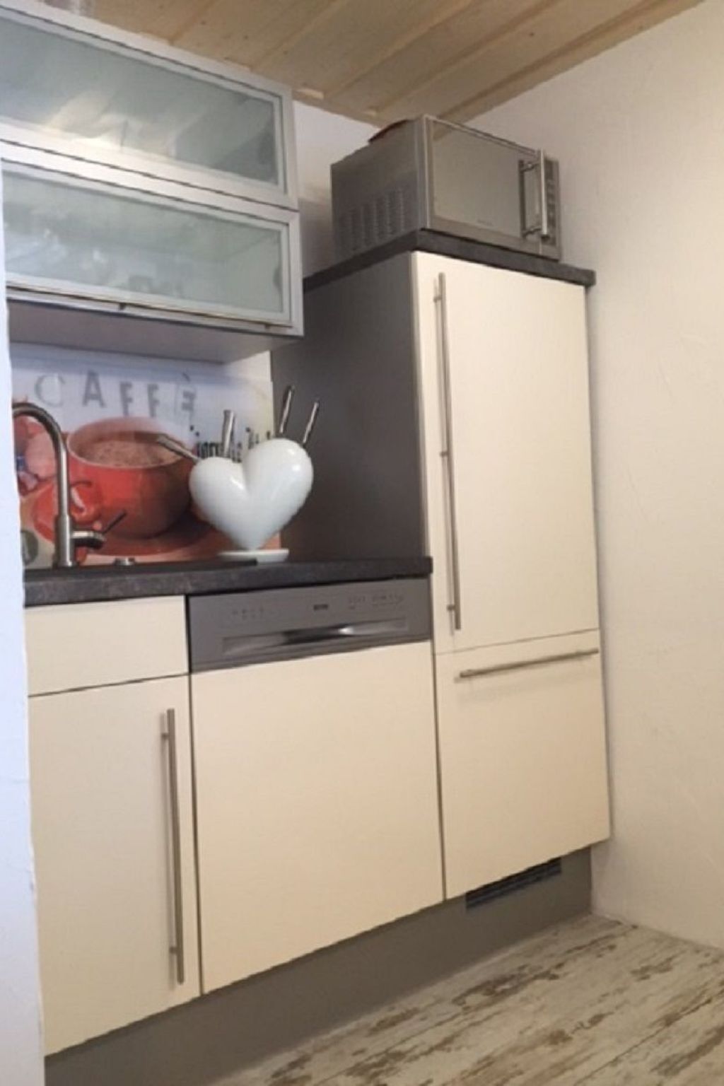 Une cuisine équipée d’un lave-vaisselle, décorée d’un ornement en forme de cœur, et comprenant un meuble de rangement sur lequel est posé un four à micro-ondes.