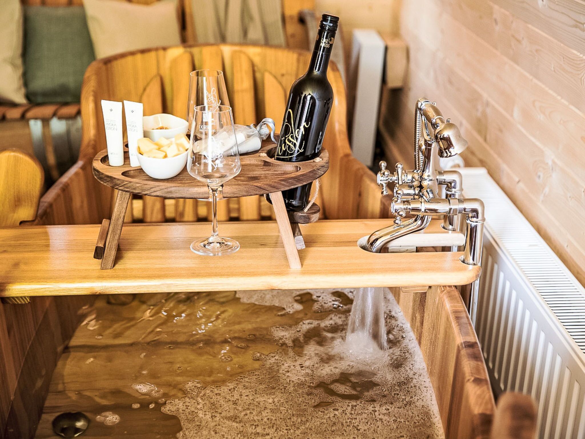 Un comptoir en bois avec une bouteille de vin, des verres et un saladier rempli de fruits.