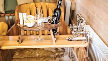 Un comptoir en bois avec une bouteille de vin, des verres et un saladier rempli de fruits.