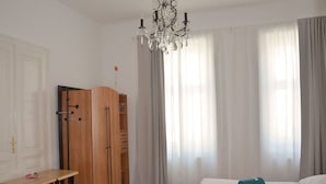 Ein Schlafzimmer mit einem Holfisch, einem Schreibtisch, einem Bett mit türkisblauen Kissen und einem Kronleuchter.
