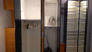 Un vestidor amplio con armario espejado, un ventilador y un zapatero.