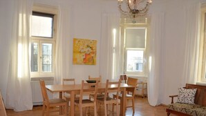 Ett rymligt vardagsrum med ett matbord och stolar i trä, en soffa och en kristallkrona.