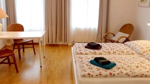 Hotellihuone, jossa on sänky, tuoli, työpöytä ja lamppu.