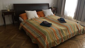 Een hotelkamer met een groot bed, twee nachtkastjes en een raam met gordijnen.
