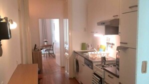 Een kleine keuken met een houten tafel, een wasmachine en een fornuis.