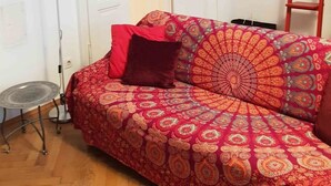 Et værelse med en stribet sofa, et lille sofabord, en gulvlampe og en stige op ad væggen.