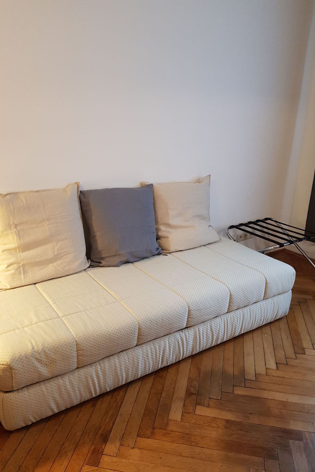 Un canapé à motifs matelassés et trois coussins aux tons neutres.