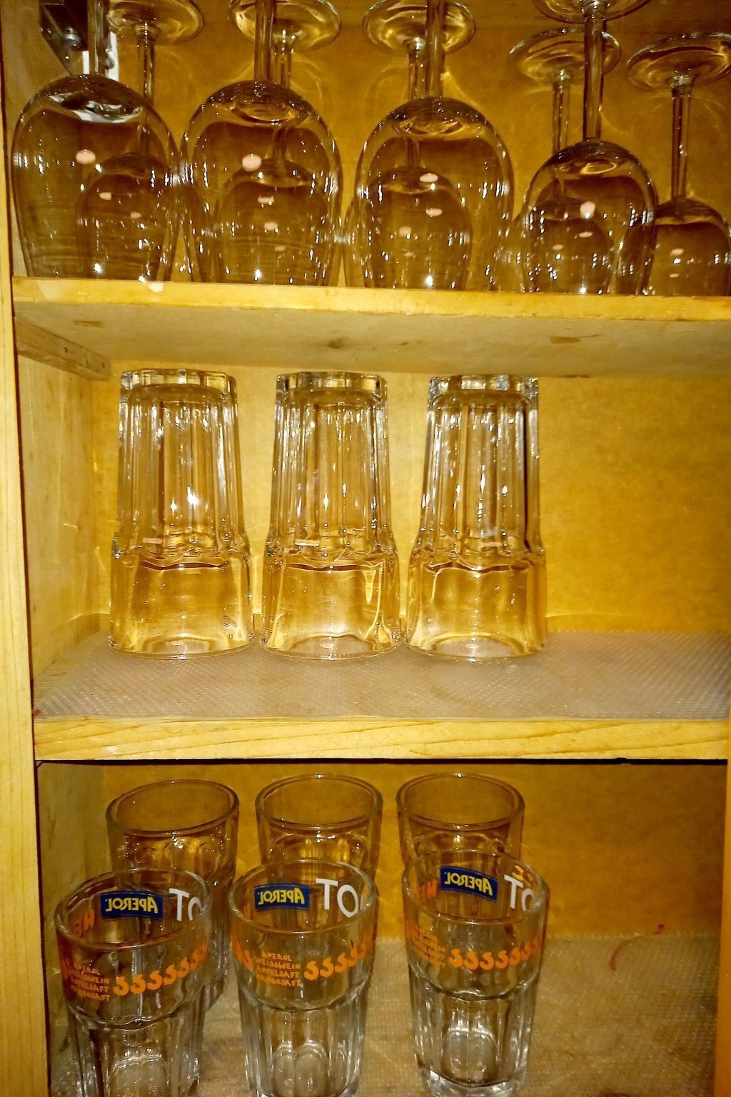 Une étagère où sont rangés, de manière ordonnée, différents types de verres, notamment des verres à vin et des verres à cocktail.