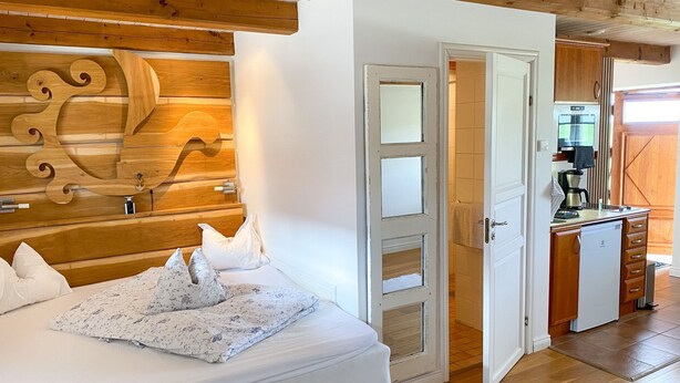 Ein Schlafzimmer mit einem hölzernen Kopfstück, einem Bett mit weißer Bettwäsche und einem Holzboden.