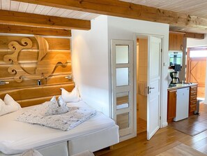 Une chambre à coucher avec une tête de lit en bois, un lit recouvert de draps blancs et un plancher en bois.