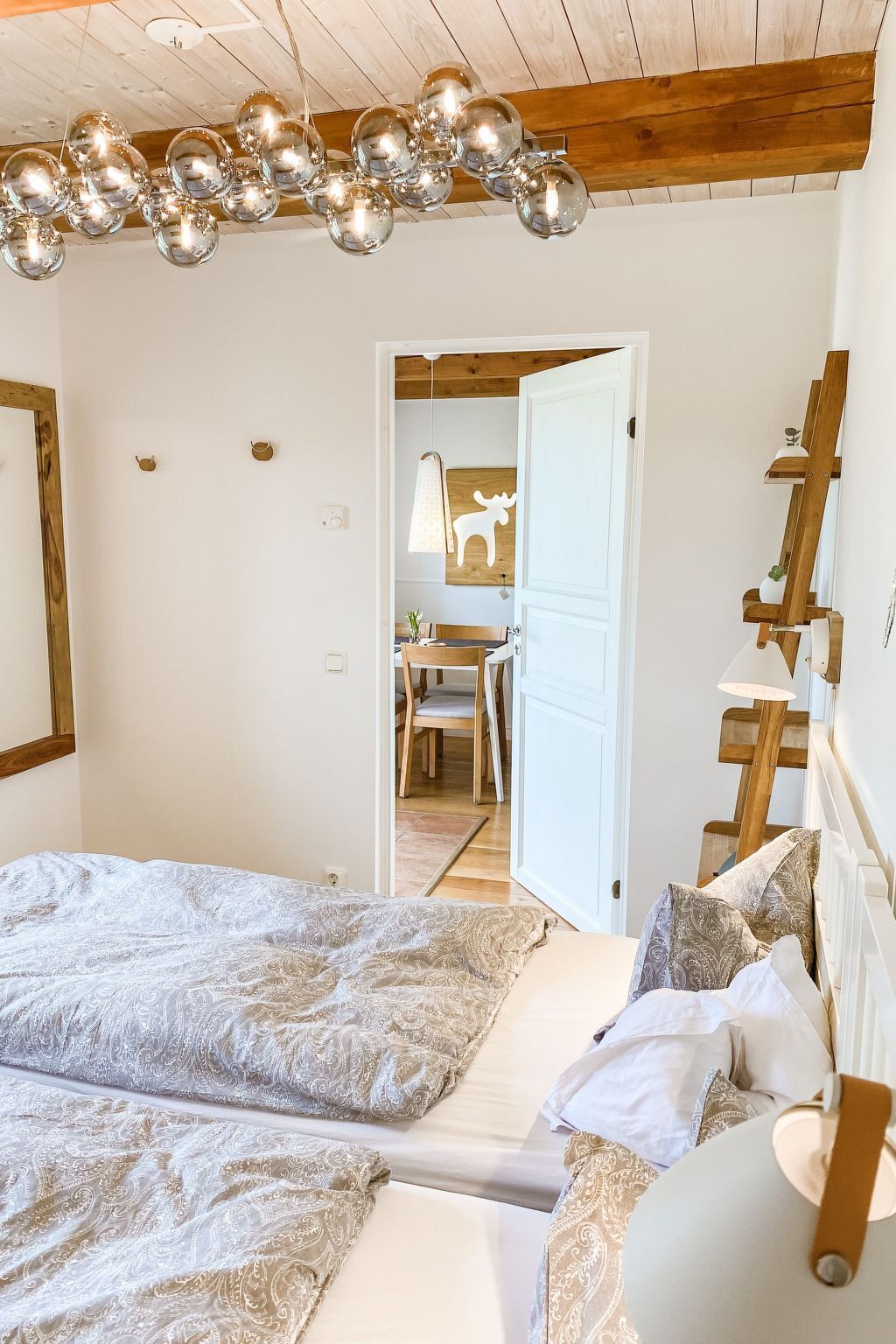 A bedroom with a large bed, a wooden ceiling, and a hanging light fixture.