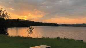 Ett picknickbord vid en sjö med utsikt över sjön och skogen under solnedgången.