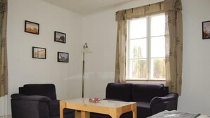 Una sala de estar con dos sofás, una mesa de centro y una lámpara. Cuatro cuadros enmarcados decoran la pared.