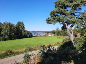 A rural landscape with a clear sky, a large green field, a few houses, and a body of water in the background. - am Algunnensee mit Sprudelwanne by Interhome (Rörvik)