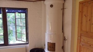 Una stanza con un termosifone cilindrico di grandi dimensioni, una finestra vista verde e una porta in legno.