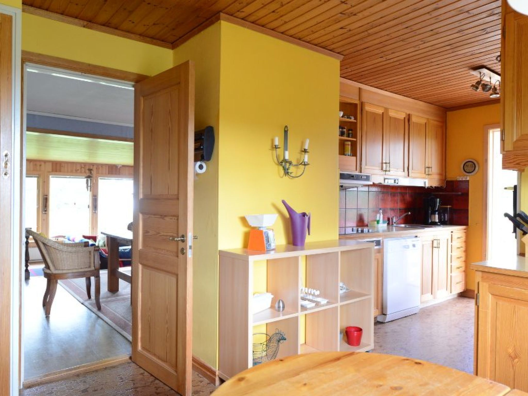 Eine Küche mit Holzausstattung, einer gelben Wand und einem Essbereich mit Stuhl und Tisch.