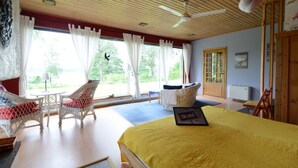 A room with a bed, two wicker chairs, a table, and a view of the outdoors. - Lilla Sjöbo by Interhome (Hok)