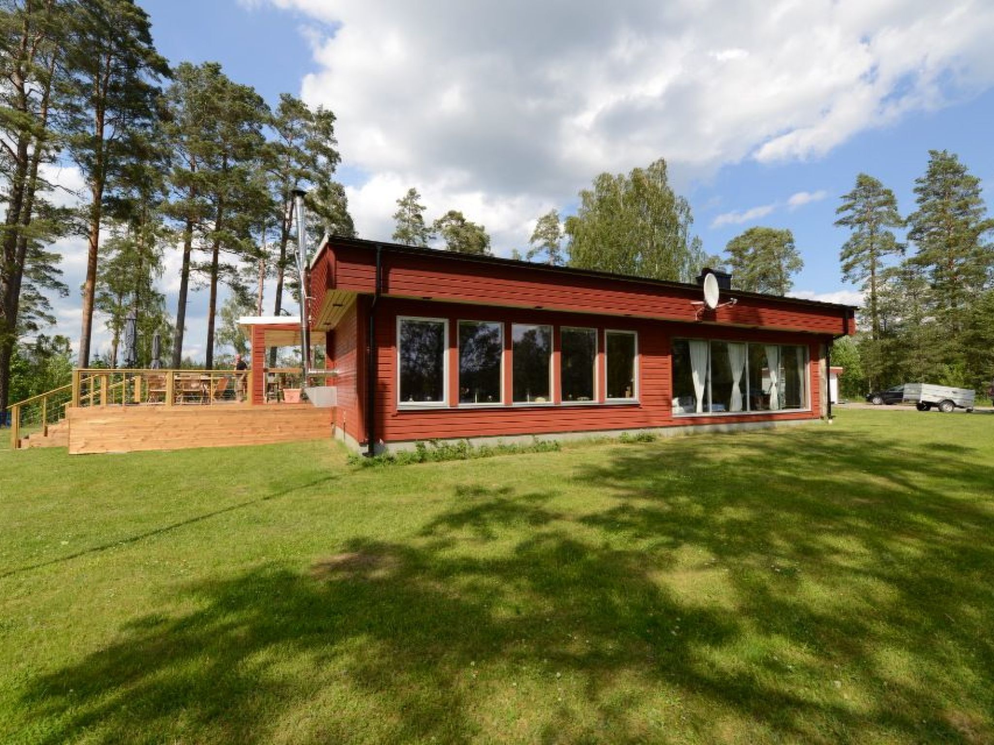 A red building with large windows, a covered deck, and a satellite dish.