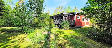 Una casa de madera rústica con fachada roja, rodeada de exuberante follaje y árboles.