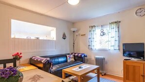A cozy living room with a sofa, a coffee table, a TV, and a window with curtains. - Gemütliches Ferienhaus in Seenähe by Interhome (Hallaryd)