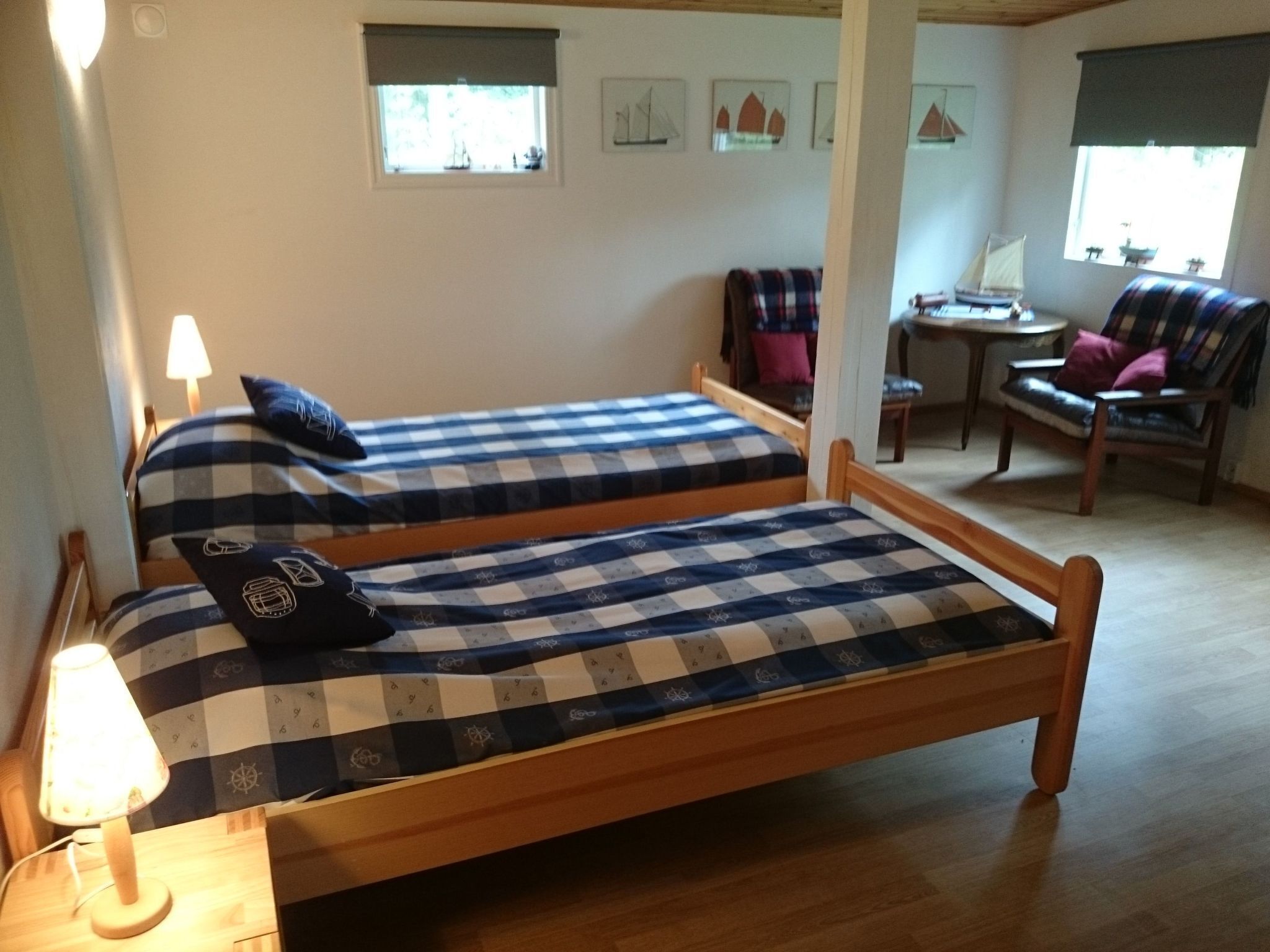 A room with two wooden beds, a small table, and a chair.