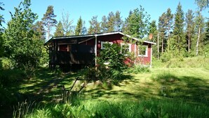 A rustic cabin with a sloped roof, surrounded by dense greenery and tall trees. - Gemütliches Ferienhaus in Seenähe by Interhome (Hallaryd)