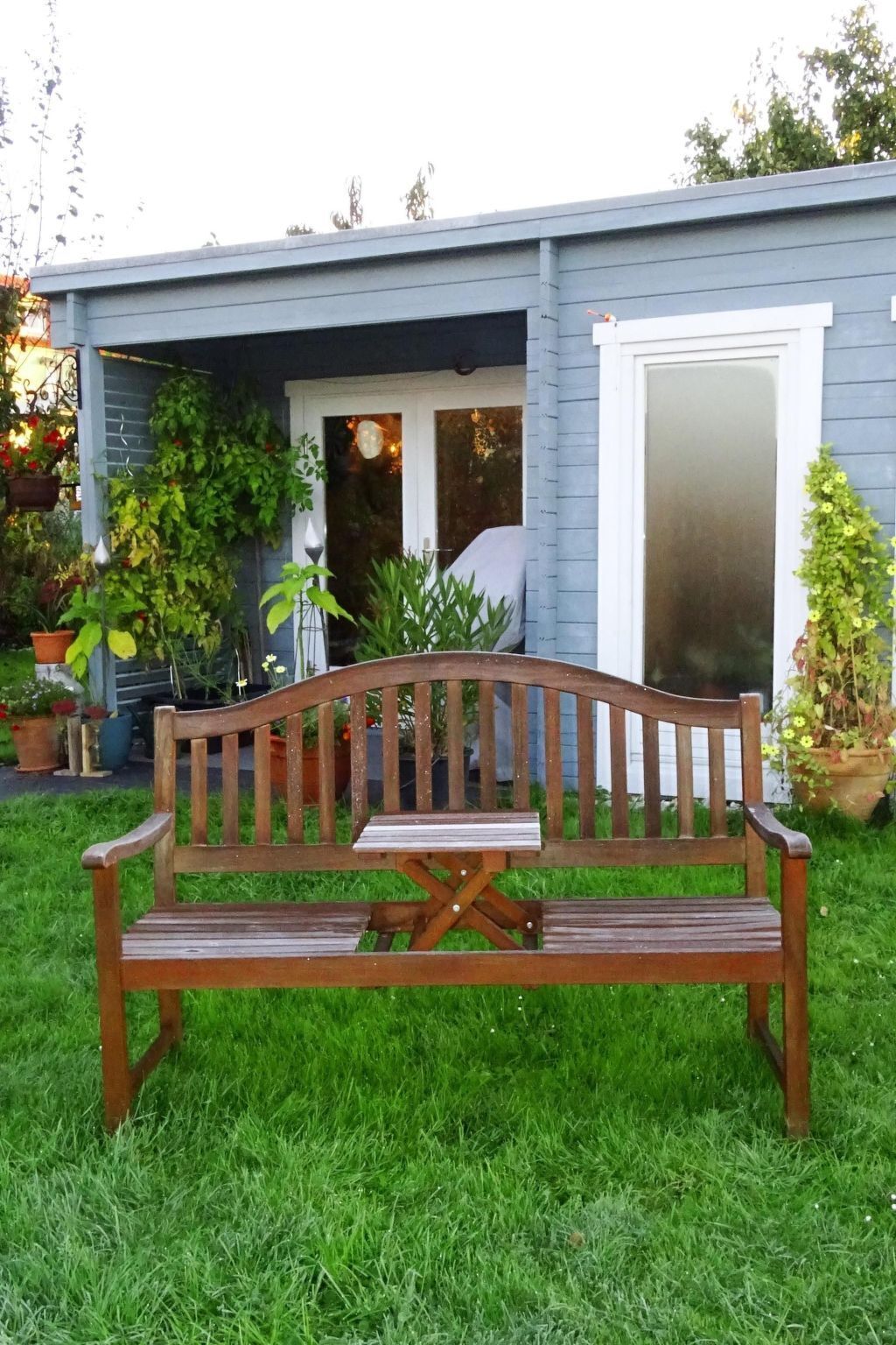 A wooden bench in a garden area with a house in the background.