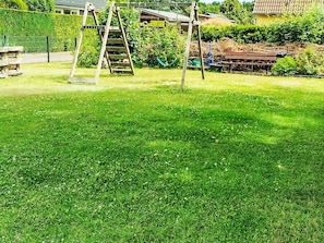Ein Rasen mit Schaukel und einer Holzleiter.