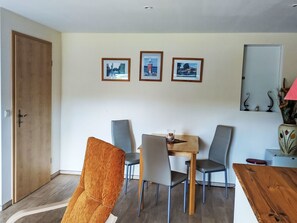 Een eetruimte met een houten tafel, vier stoelen en drie ingekaderde foto's aan de muur.