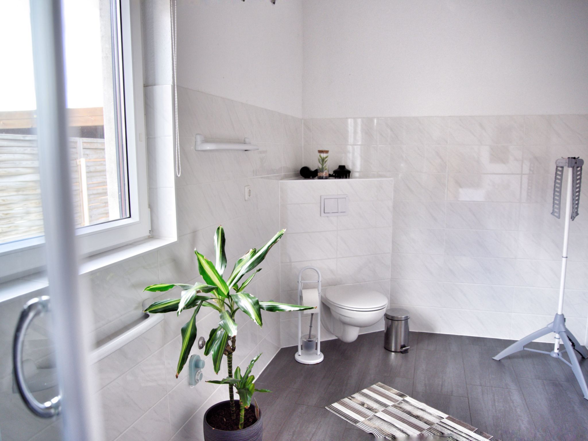 Un baño moderno con inodoro, bidé y una planta en maceta.