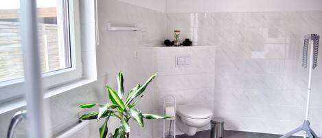 Un baño moderno con inodoro, bidé y una planta en maceta.