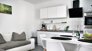 Een moderne keuken met witte kasten, een inbouwoven en een eethoek met witte stoelen en een centraal eiland.