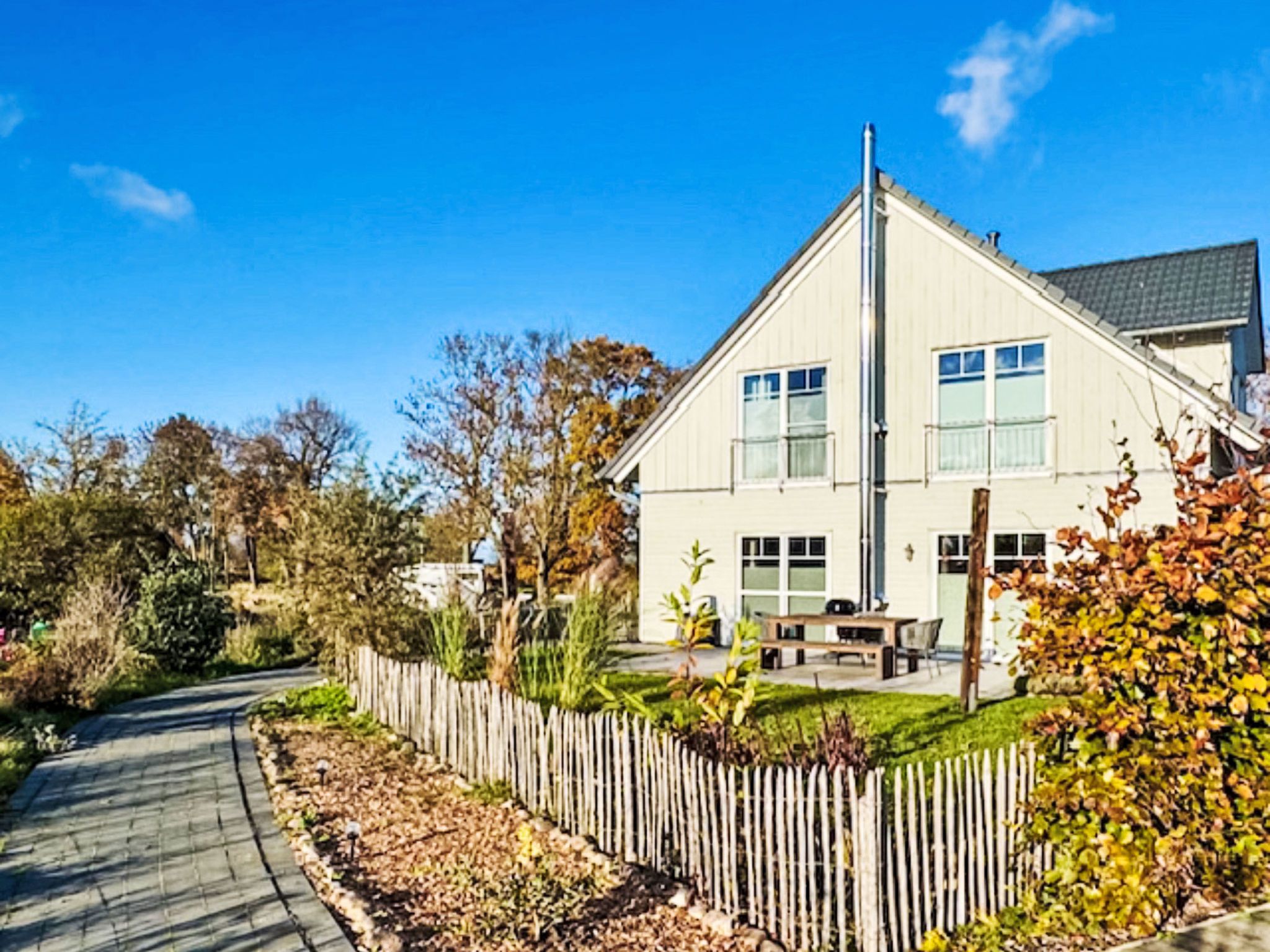 A two-story house with a visible front yard, a wooden fence, and a paved driveway.