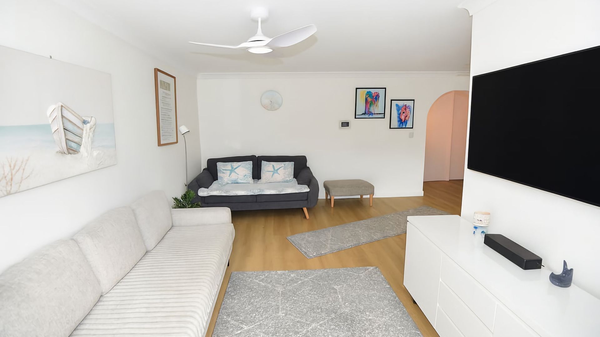 A living room with a sofa, a small table, a TV, and artwork on the walls.