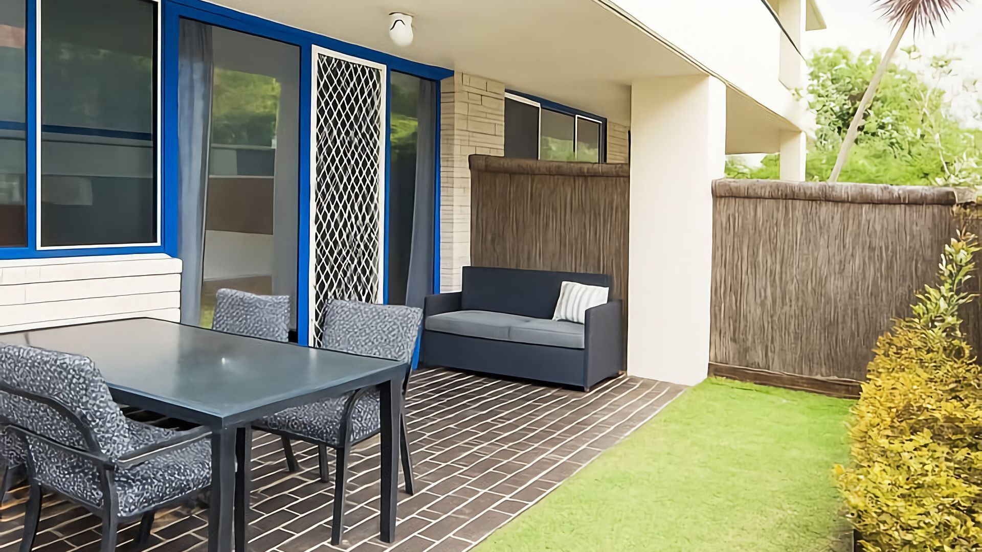 Un patio con mesa y sillas, un sofá y una valla de madera.