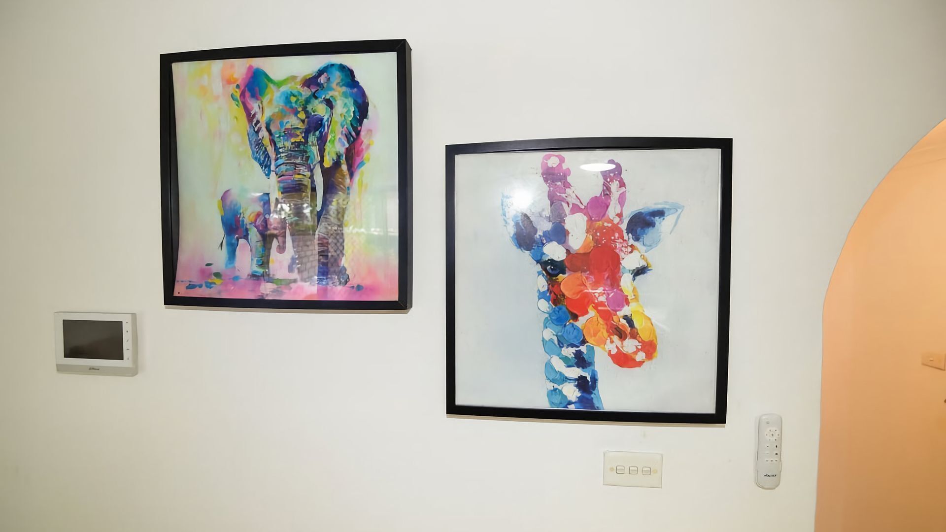 Two framed artworks on a wall, a thermostat, and a power outlet.
