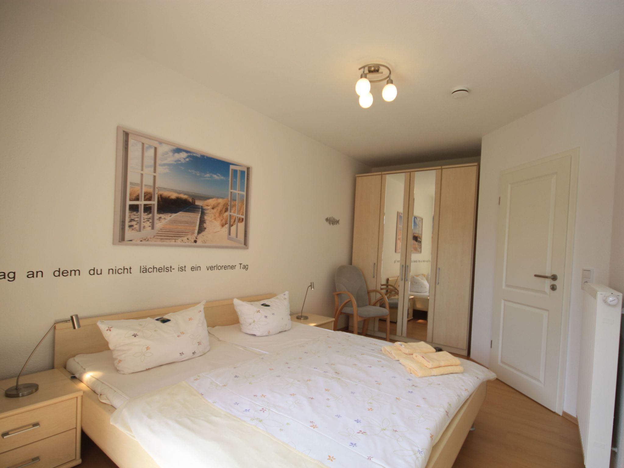 Ein Schlafzimmer mit Bett, Nachttisch, Lampe und Kleiderschrank.