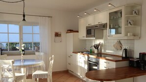 Una cucina moderna con pensili bianchi, un piano di lavoro in legno e un'area pranzo con sedie bianche.