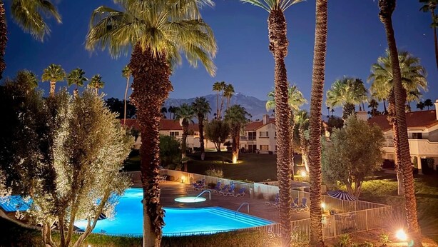 Ein Nachtblick auf ein Resort mit Schwimmbad, Palmen und Bergblick.