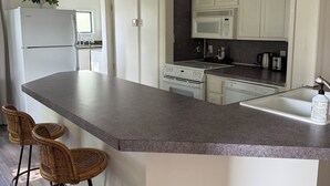A modern kitchen with a large island, white cabinetry, and a built-in microwave. - Lovely 2-bedroom cottage with AC in charming Bentonville (Bentonville)